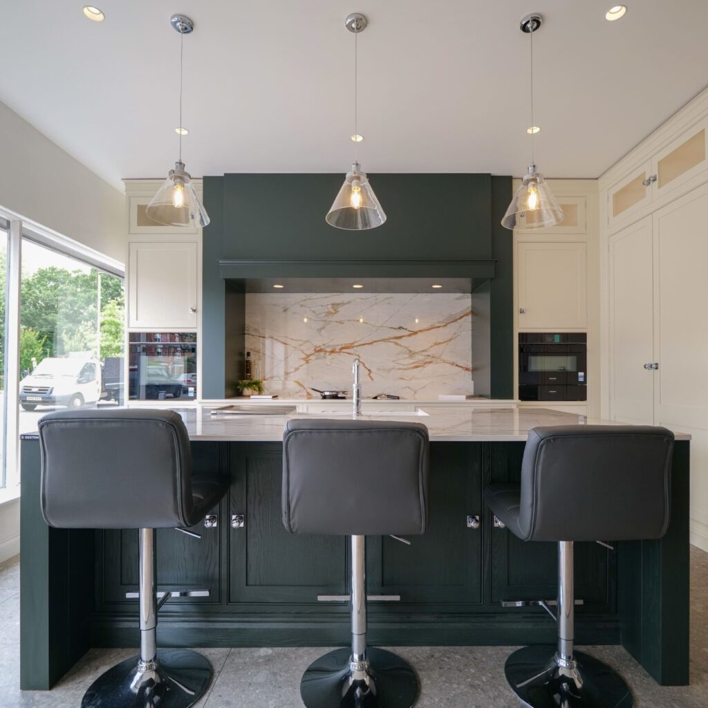 Dark green kitchen island with breakfast bar seating and marble splashback