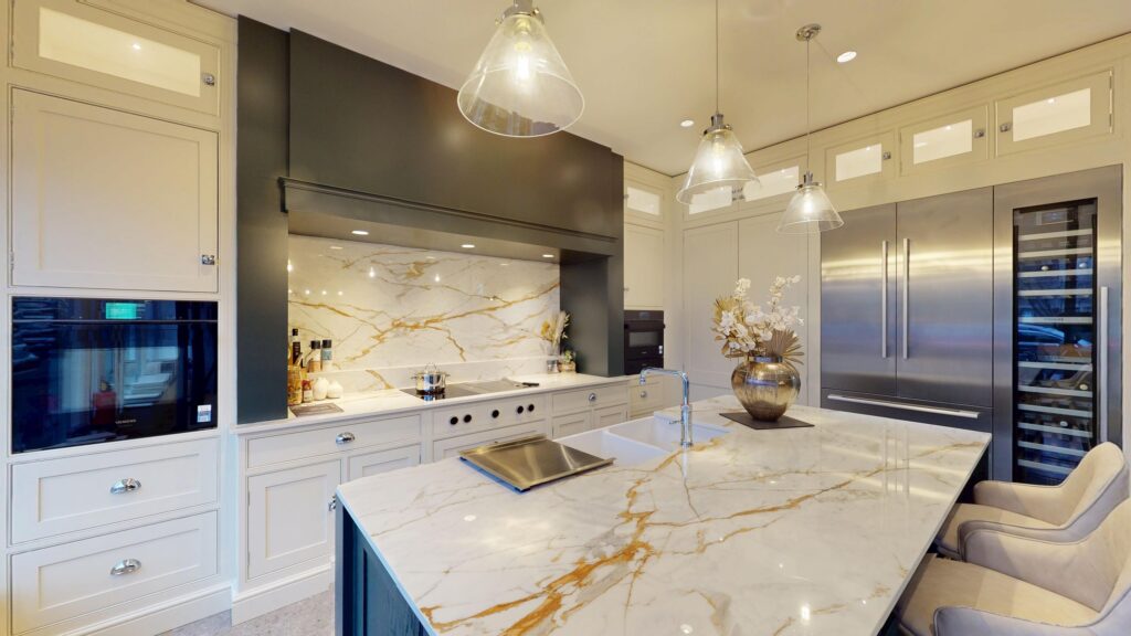 Luxury kitchen with marble island, integrated appliances, and statement pendant lights