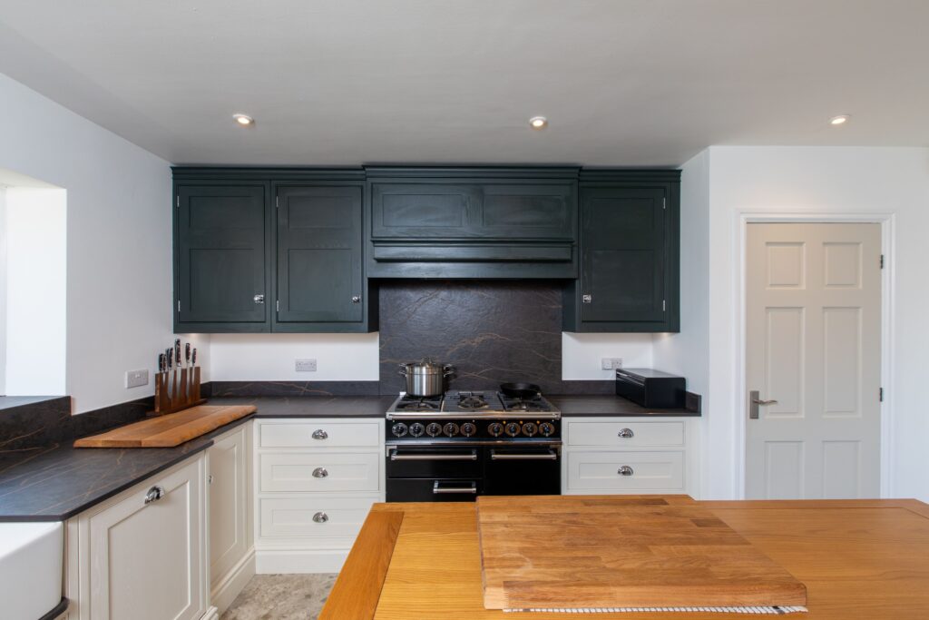 Traditional shaker kitchen with dark green wall cabinets, cream base units and range cooker