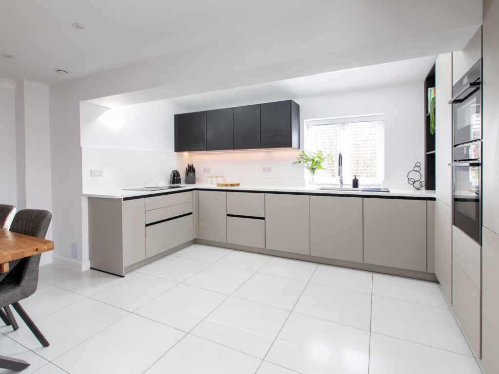 Minimalist L-shaped kitchen with neutral cabinetry, black wall units and integrated appliances