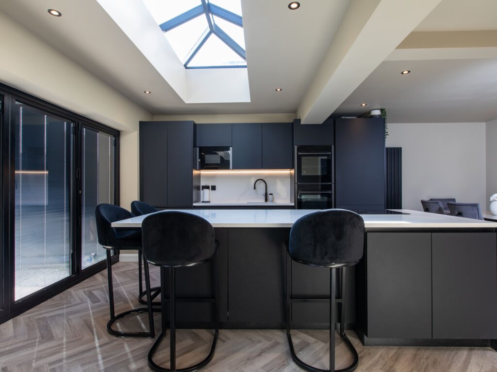 Dark modern open-plan kitchen with island seating and skylight