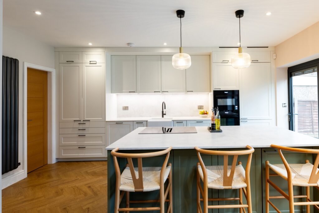Shaker kitchen with island seating, integrated appliances, and pendant lighting