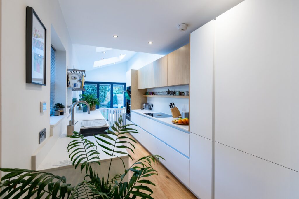 Modern white and wood kitchen extension with skylights and minimalist German kitchen furniture by Suga Küchen
